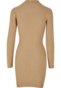 Robe à manches longues côtelée en beige, présentant une silhouette ajustée, un col rond et un tissu lisse et texturé.