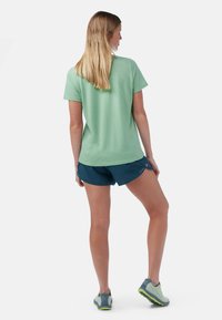 T-shirt de sport texturé vert clair associé à un short bleu foncé. Affiche une coupe décontractée avec des manches courtes et des détails subtils sur le short.