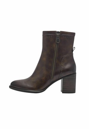 Bottine brune en cuir synthétique avec une fermeture éclair sur le côté, bout rond et talon empilé. Présente des accents cloutés le long de la tige.