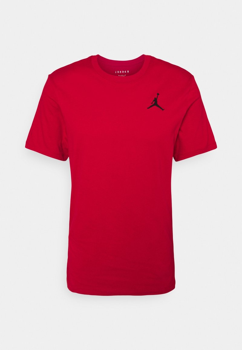 T-shirt en coton rouge avec col rond et manches courtes, arborant un logo Jordan noir imprimé sur le côté gauche de la poitrine. Texture lisse.