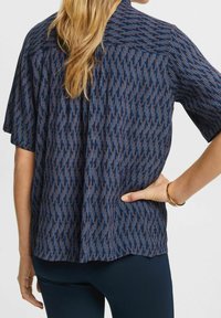Camicetta a maniche corte in tessuto navy, con un motivo testurizzato di linee verticali blu e arancioni, dal taglio dritto e vestibilità comoda.
