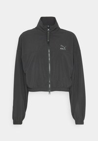 Veste courte noire Puma avec col montant, fermeture éclair complète devant, poignets élastiques et logo sur le côté gauche de la poitrine.