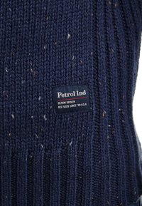 Marineblauwe gebreide trui met een geribbelde textuur en multikleurige spikkels. Inclusief een geweven label met "Petrol Ind" branding.