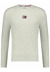 Světle šedý žebrovaný svetr s kulatým výstřihem. Obsahuje malou nášivku s logem Tommy Jeans na hrudi. Měkká, strukturovaná tkanina.