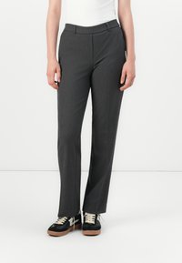 Pantalons gris sur mesure avec une coupe droite, dotés d'un devant plat, de passants de ceinture et d'une texture de tissu lisse. Associés à des baskets noires.