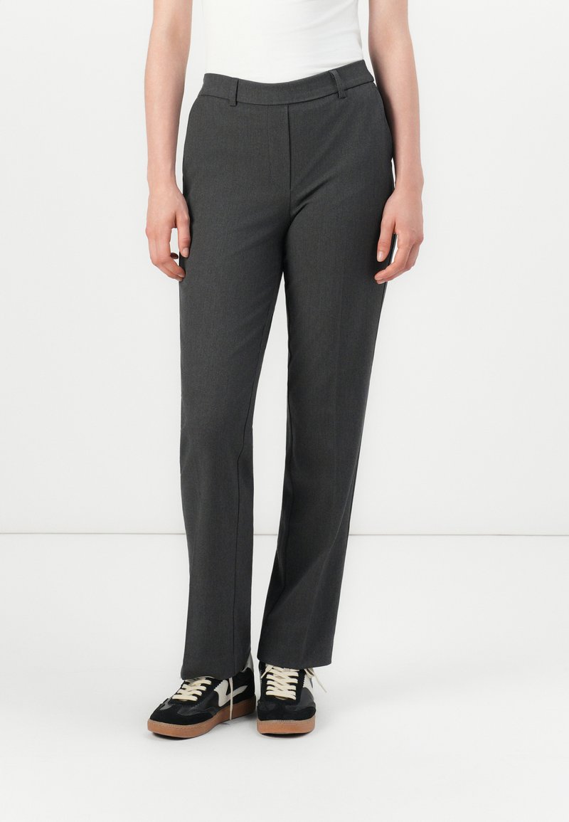 Pantalons gris sur mesure avec une coupe droite, dotés d'un devant plat, de passants de ceinture et d'une texture de tissu lisse. Associés à des baskets noires.