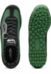 Les baskets Puma Turbo présentent un dessus en suède noir et en mesh vert, avec une semelle en caoutchouc vert texturé et des accents de marque sur le côté et la languette.