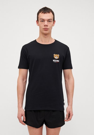 T-shirt in cotone nero con maniche corte, scollatura rotonda e logo di un orso sul lato sinistro del petto. Presenta una texture morbida e una vestibilità casual.