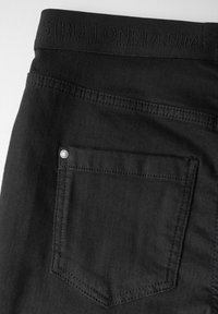 Svarta denimjeans med en bakficka med en silvernitar och präglad midja. Slät textur och klassisk design.