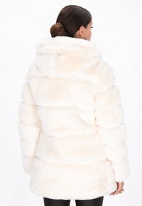 Faux fur pufferjas in zacht roomkleurig, met een capuchon, verticale doorgestikte secties en een iets langere zoom aan de achterkant.