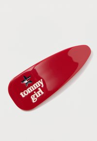 Vörös műanyag hajcsat fényes felülettel, rajta a "tommy girl" felirattal fehér színben és kék csillag díszítéssel.