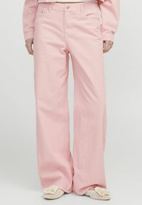 Ružičaste hlače širokih nogavica s vertikalnim bijelim prugama. Izrađene su od mekog materijala, a sadrže klasičan dizajn s pet džepova i zatvaranjem na patentni zatvarač.