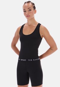 Fekete sportegyrészes ruha, lekerekített nyakkivágással, testhez simuló fazonnal és logóval díszített derékrésszel. Az anyag rugalmasnak és simának tűnik.