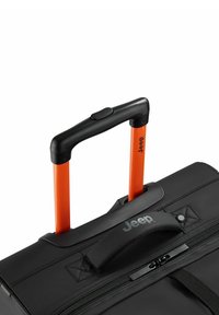 Valigia nera con ruote e manico arancione retrattile, dotata di impugnatura in gomma e logo brandizzato. Chiusura con cerniera e tessuto texturizzato.