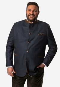 Marineblauw jack met een gestructureerde stof, bruine accenten, ronde kraag en knoopsluitingen; heeft een pochette in een geruit patroon.