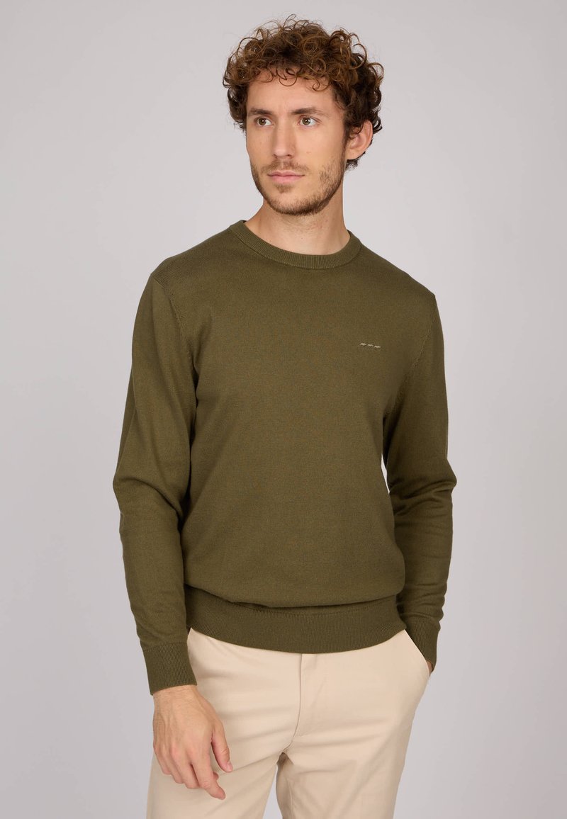 Pull en maille vert olive avec un col rond et des poignets côtelés. Présente une coupe ajustée et un logo discret sur la poitrine.