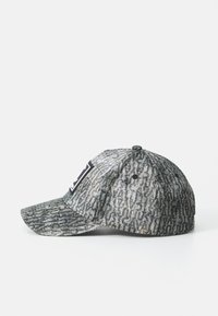 Gorra de béisbol texturizada en gris y negro con un parche en relieve en la parte frontal, mostrada de lado sobre un fondo blanco.