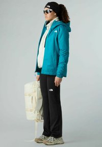 Giacca impermeabile verde acqua, felpa bianca, pantaloni neri, sneakers grigie. Tieni uno zaino color crema con le cinghie. Accessori: berretto nero, occhiali da sole.