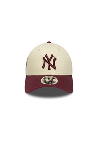 Baseball cap in cream with a maroon visor. Features a maroon embroidered "NY" logo on the front and a circular logo patch on the side.