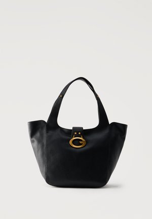 Sac à main en cuir noir avec une anse unique et une boucle ovale dorée centrée sur le devant sur un fond uni.