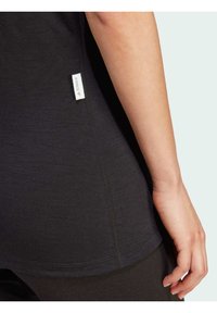 Black short-sleeve shirt with a fitted design, smooth texture, and a small white label on the side seam. Seam detailing is visible.