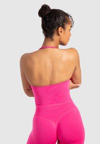 Top sportivo aderente in tessuto rosa vivace, con scollo all'americana e design senza cuciture, abbinato a leggings a vita alta coordinati.