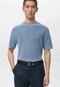 Světlé modré pletené tričko s krátkým rukávem a kulatým výstřihem, doplněné tmavými kalhotami a černým páskem, s hladkým, texturovaným povrchem.