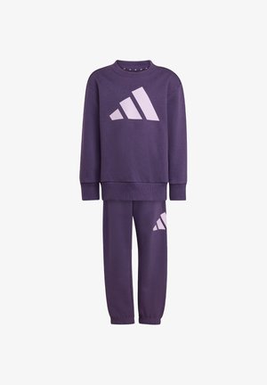 Fioletowy komplet bluzy i spodni, wykonany z miękkiego materiału, z dużym różowym logo Adidas z przodu i z boku. Ściągacze przy mankietach i dekolcie.