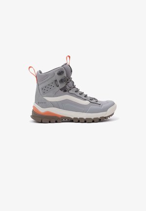 Bota de senderismo alta gris con detalles en naranja, suela marrón resistente, cordones delanteros y material impermeable Gore-Tex.