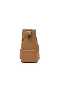 Braune Wildleder-Stiefelette mit strukturierter Oberfläche, gepolstertem Knöchelkragen und robustem Plateausohle. Verfügt über eine Schlaufe an der Rückseite.