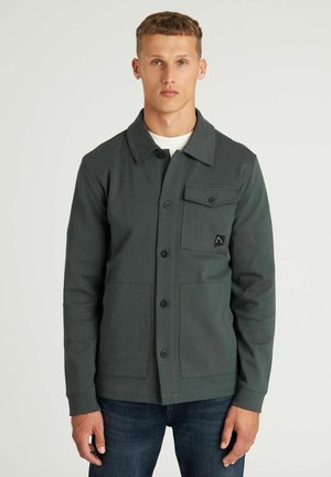 Dunkelgrüne Langarmjacke mit Kragen, einer Brusttasche, zwei frontalen Taschen und Knopfverschluss. Hergestellt aus texturiertem Stoff.