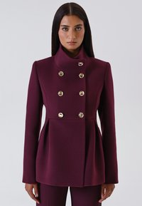 Peacoat in misto lana bordeaux con colletto alto, design doppiopetto e bottoni in tonalità oro; svasato e aderente.