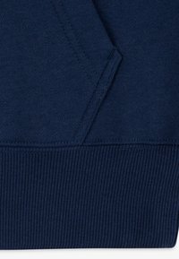 Tissu de sweat-shirt bleu marine avec une finition texturée. Présente une poche kangourou, un ourlet côtelé et des détails de couture.