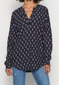 Langärmlige, marineblaue Bluse mit floralem Muster in Rot und Blau, mit V-Ausschnitt und lockerer Passform, aus leichtem Stoff gefertigt.