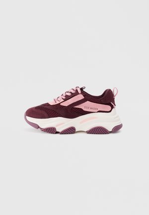 Zapatillas en color marrón y rosa con acentos de malla y ante, suela intermedia blanca gruesa, suela de goma y una marca destacada en el lateral.