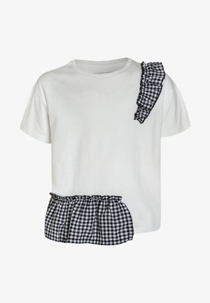 T-shirt blanc à manches courtes avec des volants à carreaux noirs et blancs sur l'épaule gauche et près de l'ourlet inférieur côté droit.