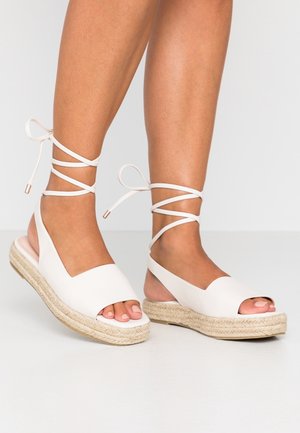 Hvide åbne espadrille-sandaler med flettet jutesål, bindebånd ved anklen, glat læderoverdel og lav kilehæl.