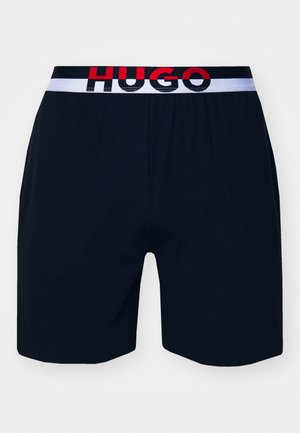 Navy cotton boxer shorts with an elastic white waistband featuring black and red "HUGO" logo text. Simple design with a smooth texture.