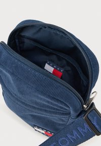 Ναυτικό τσαντάκι από κορδούρα με κλείσιμο φερμουάρ, διαθέτει επενδεδυμένο εσωτερικό και ετικέτα με το λογότυπο σε κόκκινο, λευκό και μπλε. Συμπεριλαμβάνεται ρυθμιζόμενος ιμάντας.