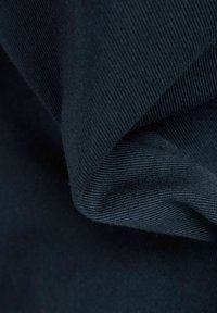 Katoenen stof in donker marineblauw, met een ribbelstructuur en plooien die zachtheid en diepte tonen. Gladde oppervlakte met een subtiele glans.