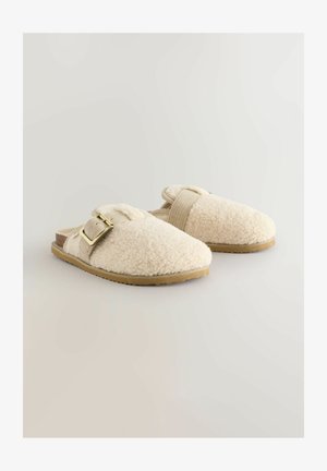 Pelsede, cremegule tøfler med en struktureret overflade, justerbar rem og metallisk spænde på en fleksibel, beige gummisål.