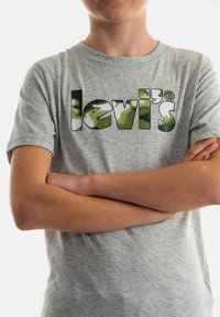 Grijze korte mouwen t-shirt met een gedurfde groene, zwarte en witte "Levi's" logo. Gemaakt van katoen en heeft een klassiek ronde hals ontwerp.