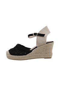 Sandale compensée en tissu noir tissé avec une semelle en jute tressé, dotée d'une sangle beige et d'une boucle réglable à la cheville.
