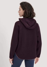 Fleece-Hoodie in dunklem Lila mit samtiger Textur, ausgestattet mit einer Kapuze mit Kordelzug und einem hohen-Tiefen Saum. Weiche Fütterung und lange Ärmel.