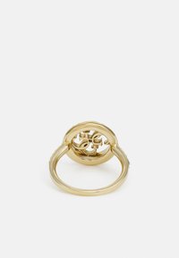 Goldring mit einem kreisförmigen Design, das ein markantes ausgeschnittenes Muster, eine glatte Textur und eine polierte Oberfläche aufweist.