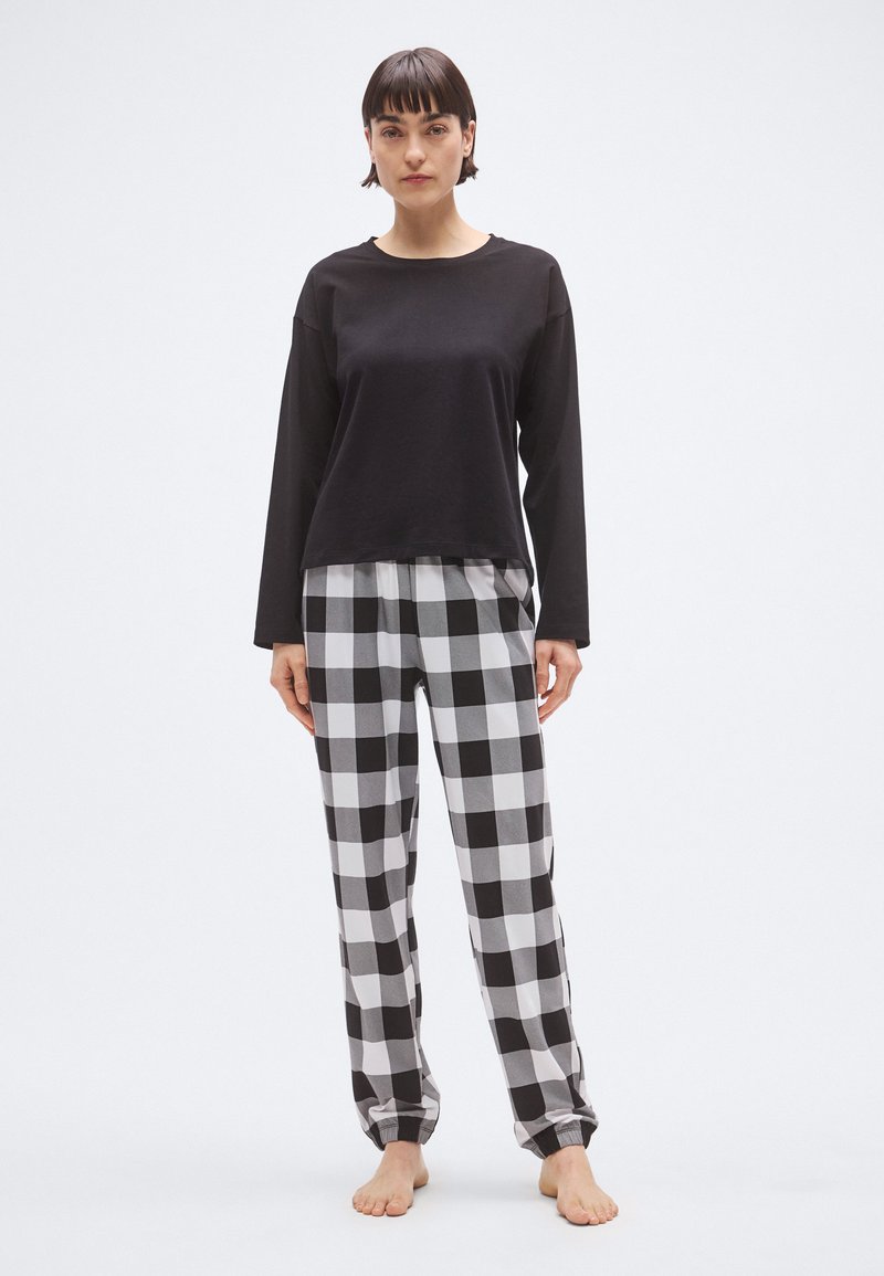 Μαύρο πουκάμισο μακρυμάνικο συνδυασμένο με πιτζάμες σε ασ πρόμαυρο καρό. Μαλακό ύφασμα, άνετη εφαρμογή και ελαστική μέση για άνεση.