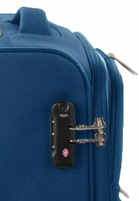 Valigia blu con doppie zip chiuse in un lucchetto combinazione TSA nero vicino al manico della valigia.