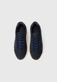 Tenisi din suede de culoare bleumarin închis, cu sireturi plate bleumarin, vârfuri rotunjite și talpă din cauciuc bej. Au un design minimalistic și nu prezintă branding vizibil.