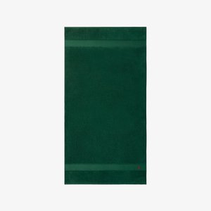 Asciugamano verde in morbido cotone, caratterizzato da un colore uniforme con una superficie testurizzata e due strisce orizzontali decorative vicino alla parte superiore.