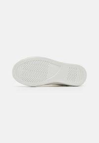 Vit sneakersula med en strukturerad yta med vågiga mönster och ett slätt område i mitten, designad för grepp.